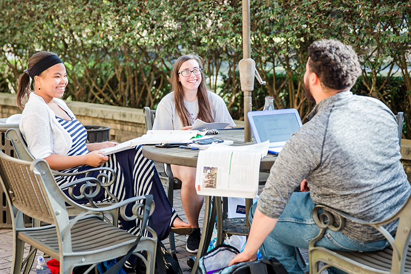 Photo of students chatting around patio table