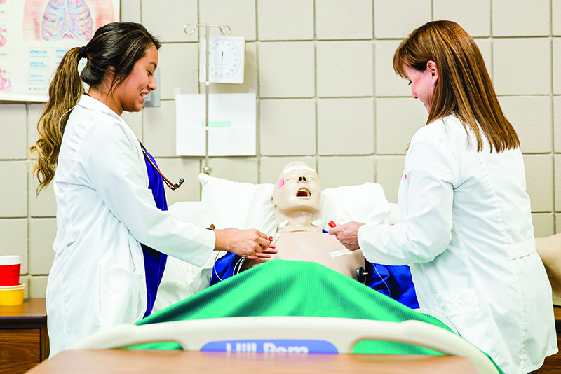 Photo of student and teaching working on nursing sim-man