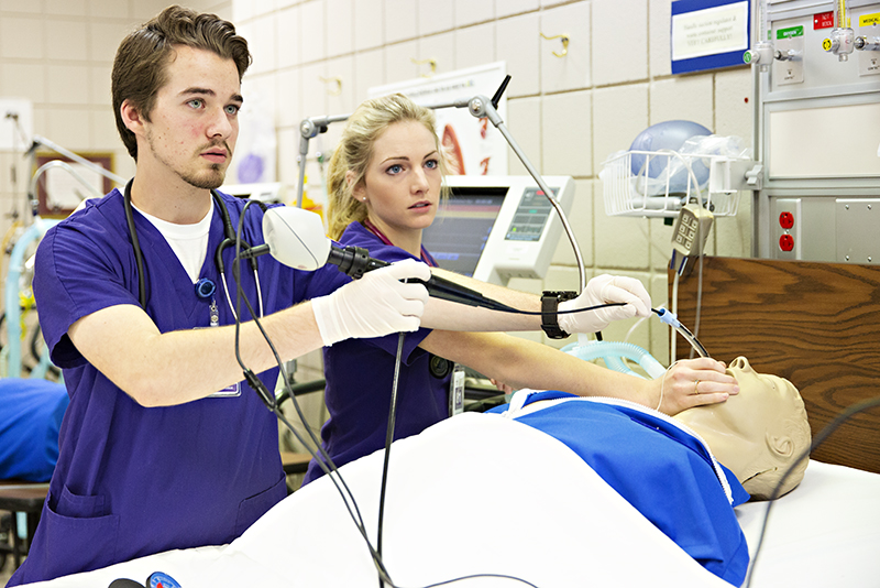 Photo of students inserting camera down throat of sim-man