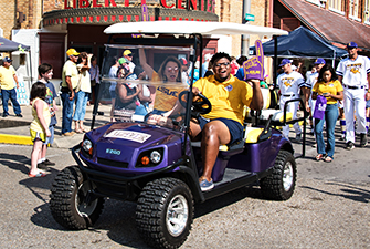 LSUE SGA president and Chancellor riding on golf cart in a parade